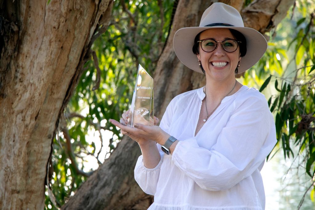 a woman holds a glass trophy