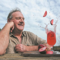 A mid shot of a man looking at apples drop into a glass.