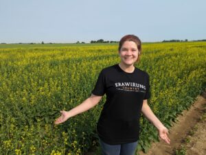 Eliza Berlage stands in a field of canola in Canada